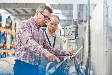 deux hommes devant une machine industrielle